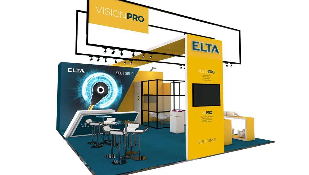 A modern ELTA trade show booth in blue and yellow promoting VISION PRO, with seating, display screens, and the text "SEE | SENSE" and "VISION PRO" prominently displayed.
