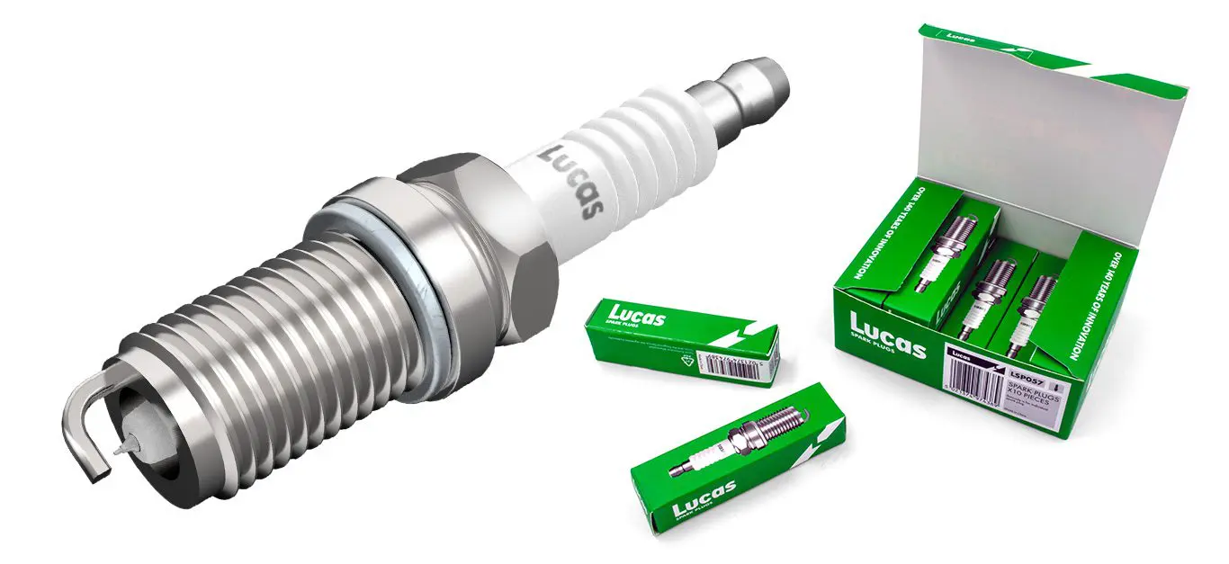 A Lucas-branded spark plug displayed next to an open green box containing three more individually boxed spark plugs, with additional smaller green boxes scattered around.
