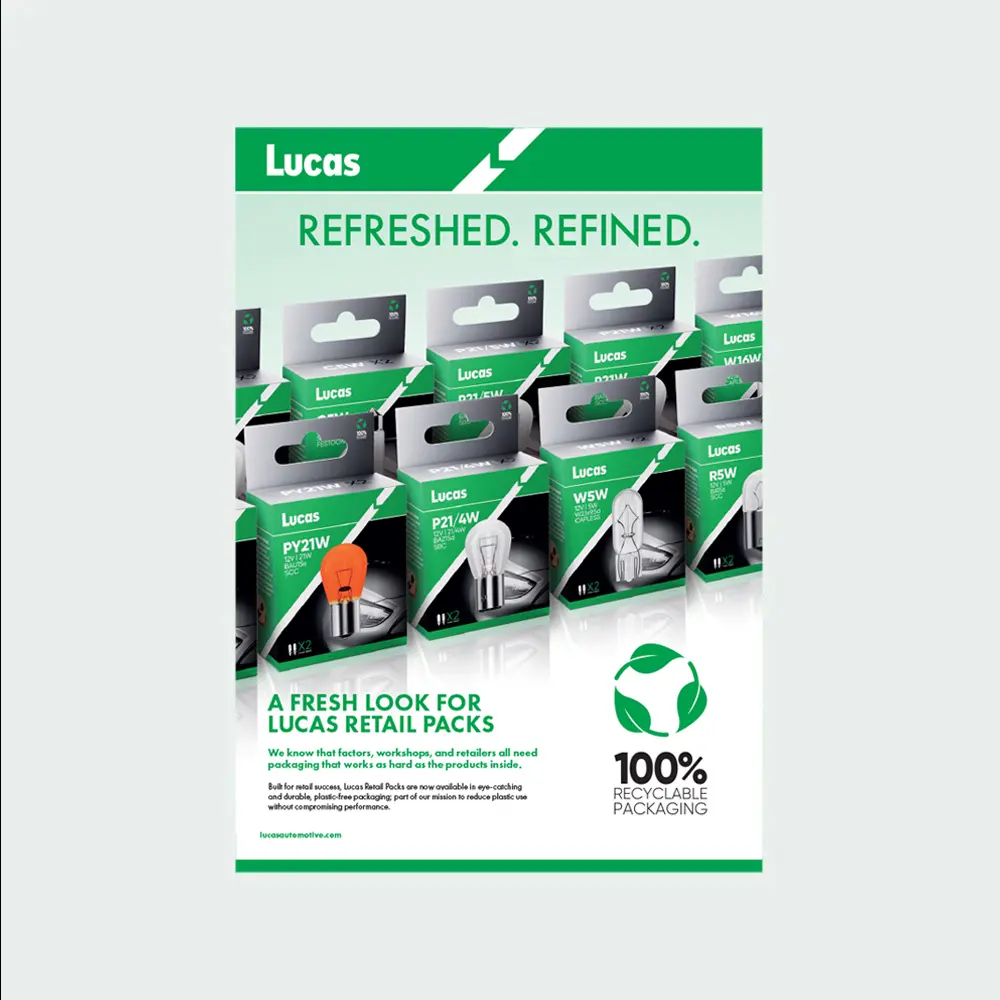 Display of multiple Lucas automotive bulb retail packs arranged in rows, featuring green and silver packaging with bulb illustrations, alongside text announcing refreshed packaging and a 100% recyclable packaging symbol.