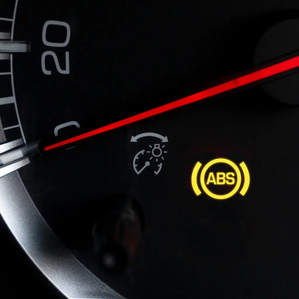 A close up of the a speedometer of a car with the ABS warning light illuminated. 