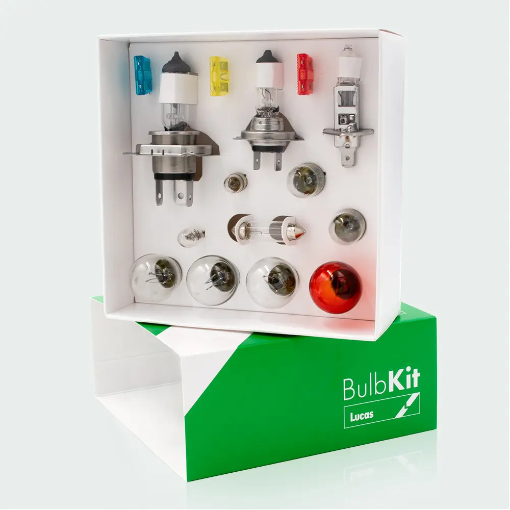 A boxed automotive bulb kit containing various vehicle bulbs and fuses, displayed inside white packaging set on top of a green box labeled “BulbKit Lucas.”
